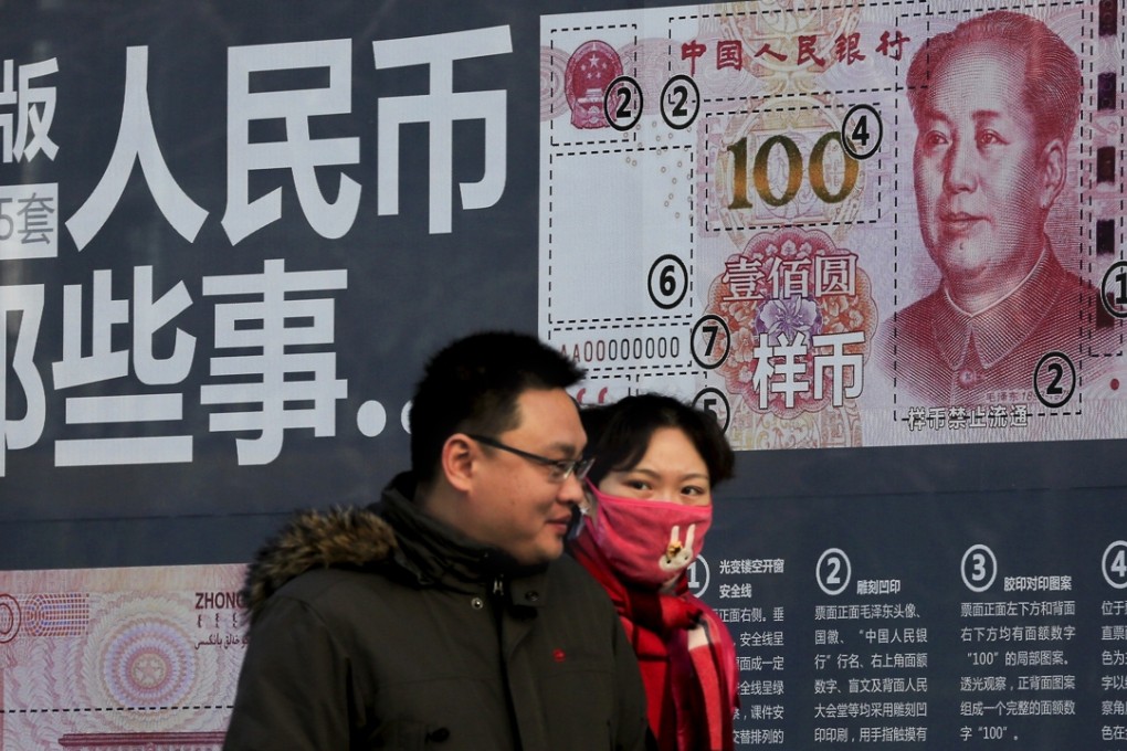 A couple walk past a display showing the security features of the new 100 yuan note in Beijing on Monday. Photo: AP