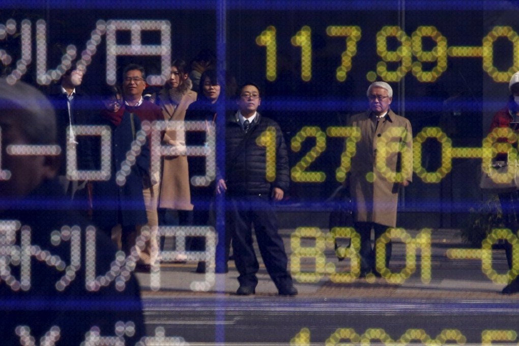 Pedestrians waiting for a traffic light in Tokyo are reflected in an electronic board showing yen exchange rates. Photo: Reuters