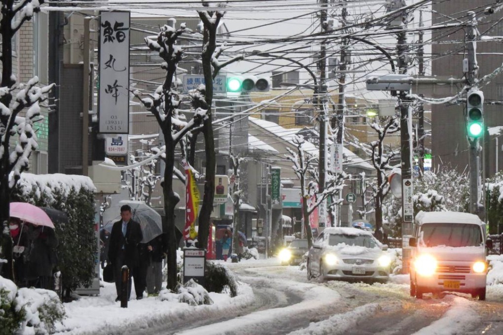 People walk along a street covered with snow as they head to a subway station in Tokyo on January 18, 2016. Photo: AFP