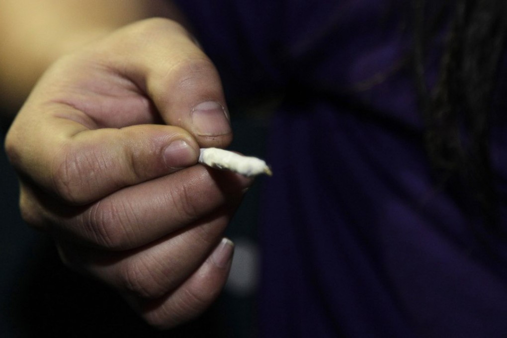 A person holds a freshly-rolled marijuana joint just after midnight at the Space Needle in Seattle. A new analysis released Monday is challenging the idea that smoking marijuana during adolescence can lead to declines in intelligence. Photo: AP