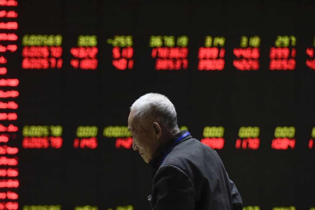 An investor walks past an electronic board showing stock information at a brokerage house in Beijing on January 18, 2016. Photo: AFP