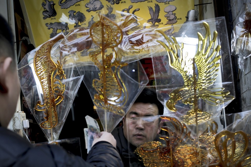 A man buys a monkey-shaped candy stick from a vendor in Qianmen Street, a popular tourist spot in Beijing. Photo: AP