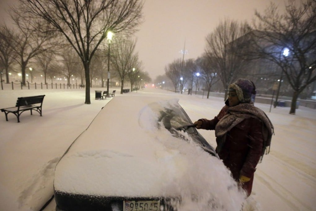 Ndimyake Mwakalyelye cleans off her car after getting off work in Washington on Friday evening. Photo: AP