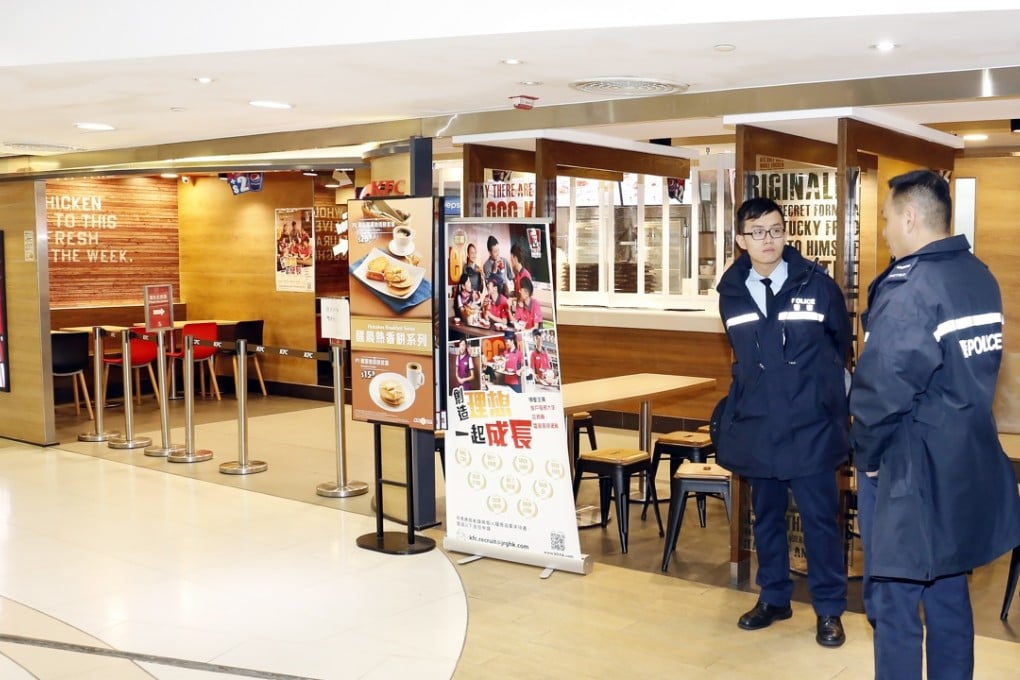 Police stand guard in the KFC outlet in Panda Place where the shotgun was left. Photo: SCMP Pictures