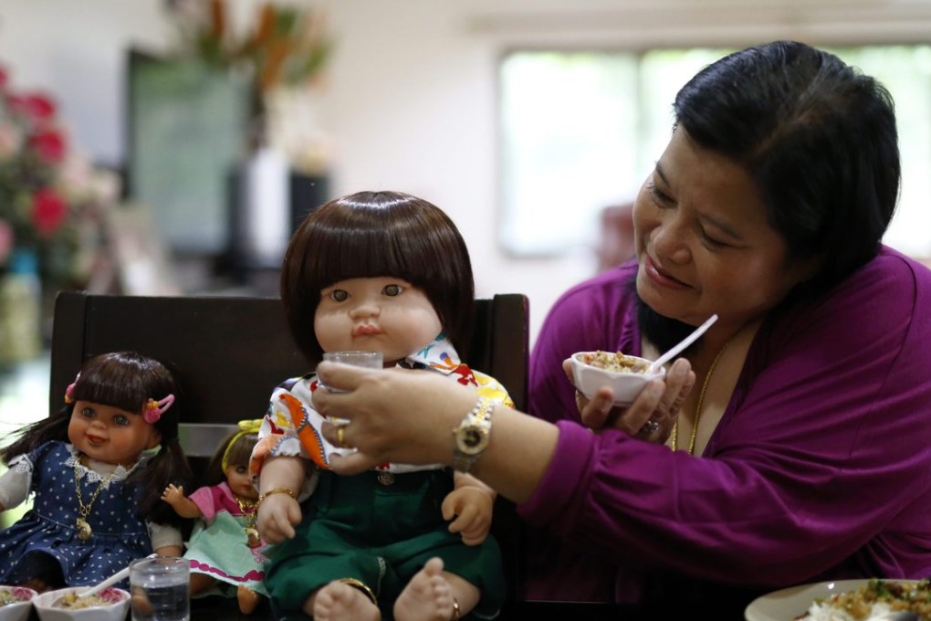 Thai devotee Ratchada Mahanavanont, 45, feeding her Child Angels Dolls while having a meal at her house in Bangkok, Thailand. Photo: EPA
