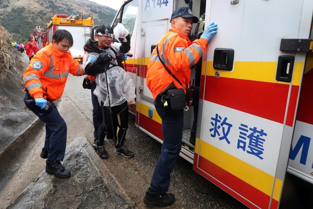 Ambulance officers help a hiker on the road leading up to Tai Mo Shan during the cold snap. Photo: Felix Wong
