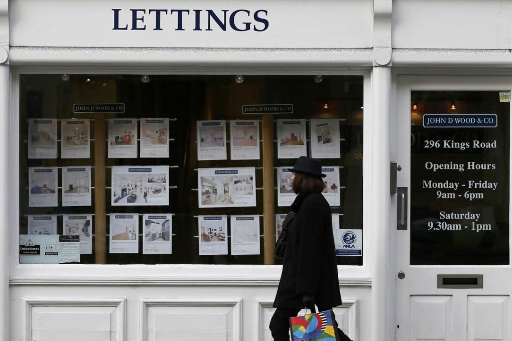 A woman walks past an estate agent in Chelsea, London. Photo: Reuters