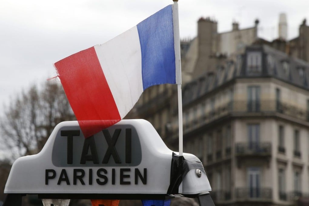 A French flag waves above a striking French taxi as drivers continue their national protest about competition from private car ride firms like Uber, in Paris, France, January 27, 2016. Photo: Reuters
