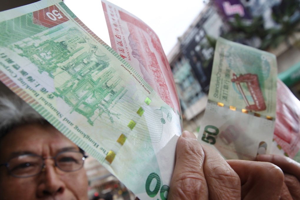 A Hongkonger holds up HK$50 and $100 banknotes as the peg to the US dollar is expected to hold despite speculative attacks against the peg linking the two currencies together. Photo: Felix Wong