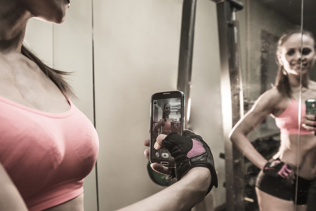 A young woman taking selfies in the gym. Instagram is one of the richest sources of advice about transforming your life.
