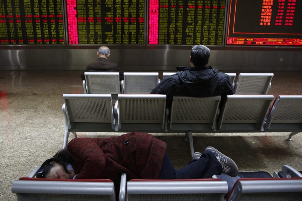 An investor takes a nap in front of an electronic board showing stock prices at a securities brokerage house in Beijing. Photo: EPA