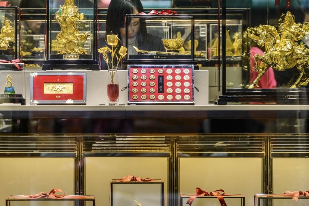 A woman stands behind a display of gold items in a jewellery shop in Hong Kong as jeweller Chow Tai Fook is being invited to open a second shopping mall in Shanghai. Photo: AFP