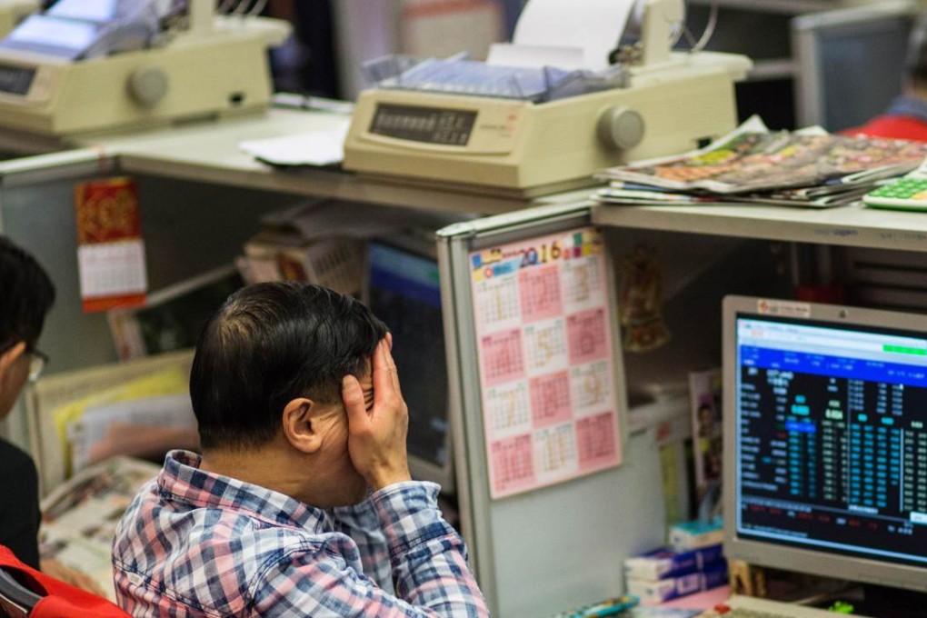 A trader reacts as he works on the trading floor of the stock exchange in Hong Kong on February 3, 2016. Hong Kong stocks plunged in the morning session on February 3 as another sell-off in oil hammered energy firms, while insurance companies were also hit by a report China would clamp down on the purchase of overseas cover. AFP PHOTO / ANTHONY WALLACE