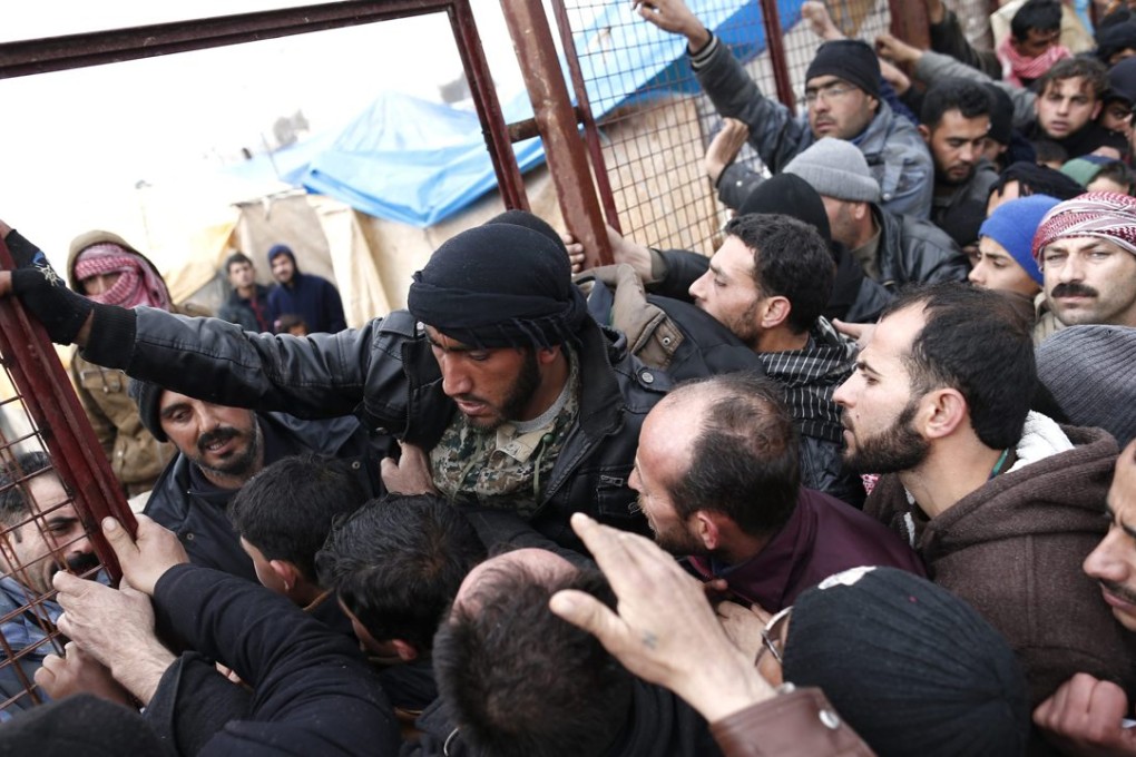 Syrian refugees wait for food near a refugee camp in Bab Al-Salama. Photo: EPA