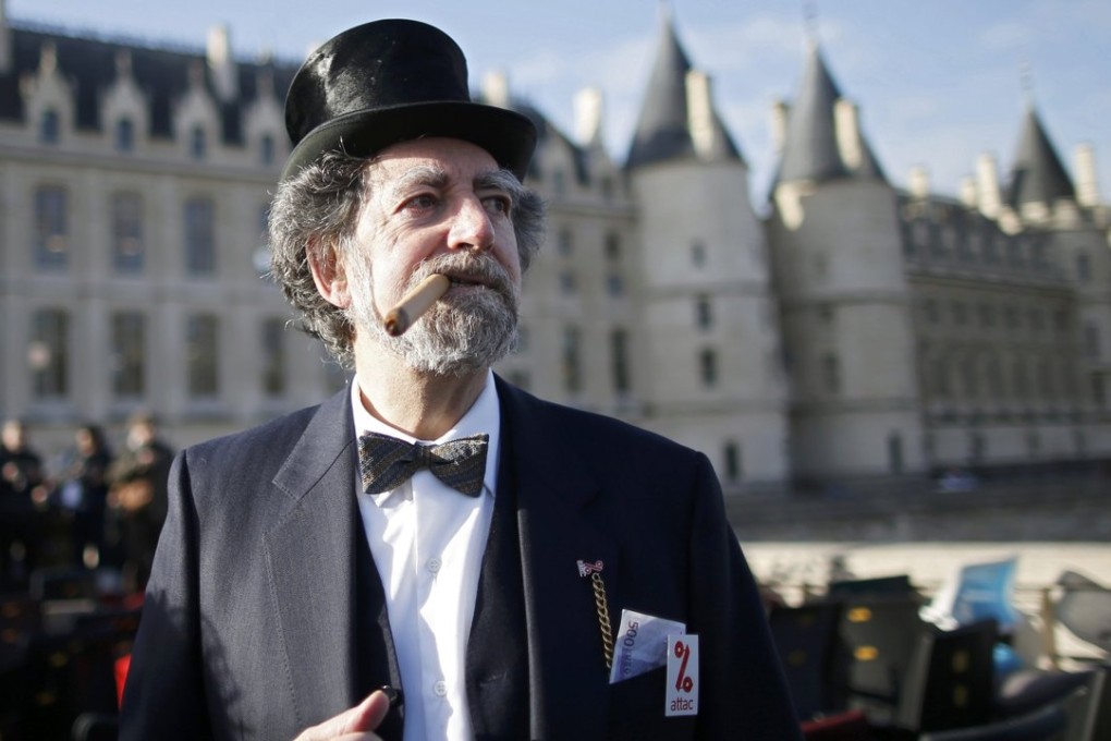 A demonstrator, dressed as a symbolic banker, stands on a bridge in Paris on Monday next to empty chairs that were stolen from bank offices in France to protest against the banking system and tax fraud. Photo: Reuters