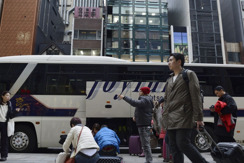 Chinese tourists pack their shopping into suitcases before loading them onto a Hino Motors Ltd. bus outside the Laox Co. Ginza store in Tokyo. Photo: Bloomberg