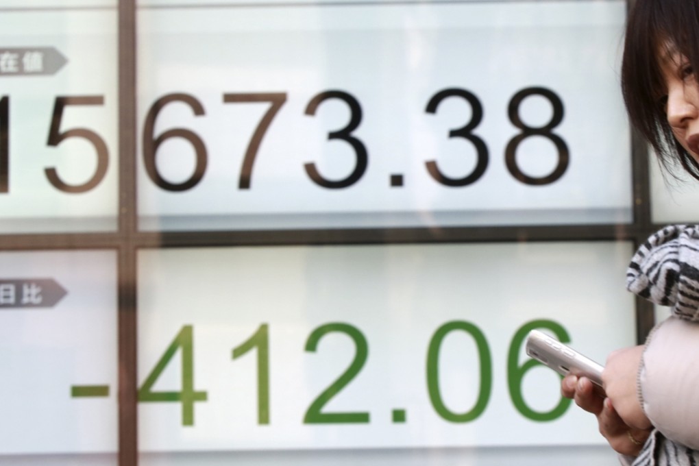 A woman walks past an electronic stock board showing Japan's Nikkei 225 in Tokyo as Asian stock markets fell for a third consecutive day on Wednesday, beset by nerves about shaky global growth, falling oil prices and possible capital shortfalls at major European banks. Photo: AP