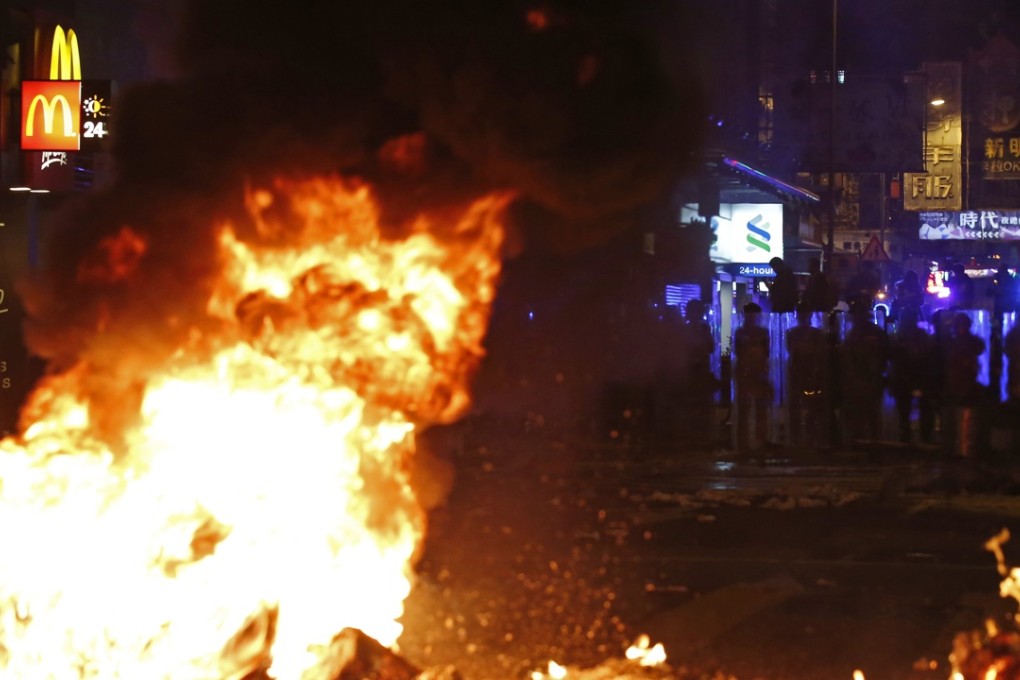 Riot police in Mong Kong during Monday night’s disturbances as a fire burns. Photo: AP