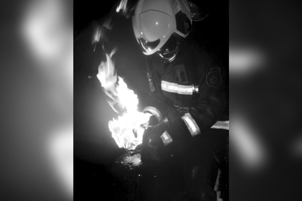 One of the firefighters pictured removing a burning gas cylinder. Photo: Beijing Times