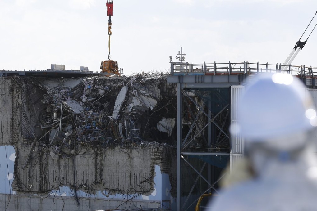 A member of the media, wearing a protective suit and a mask, looks at the damaged reactor building at the Fukushima Daiichi nuclear power plant. Photo: Reuters