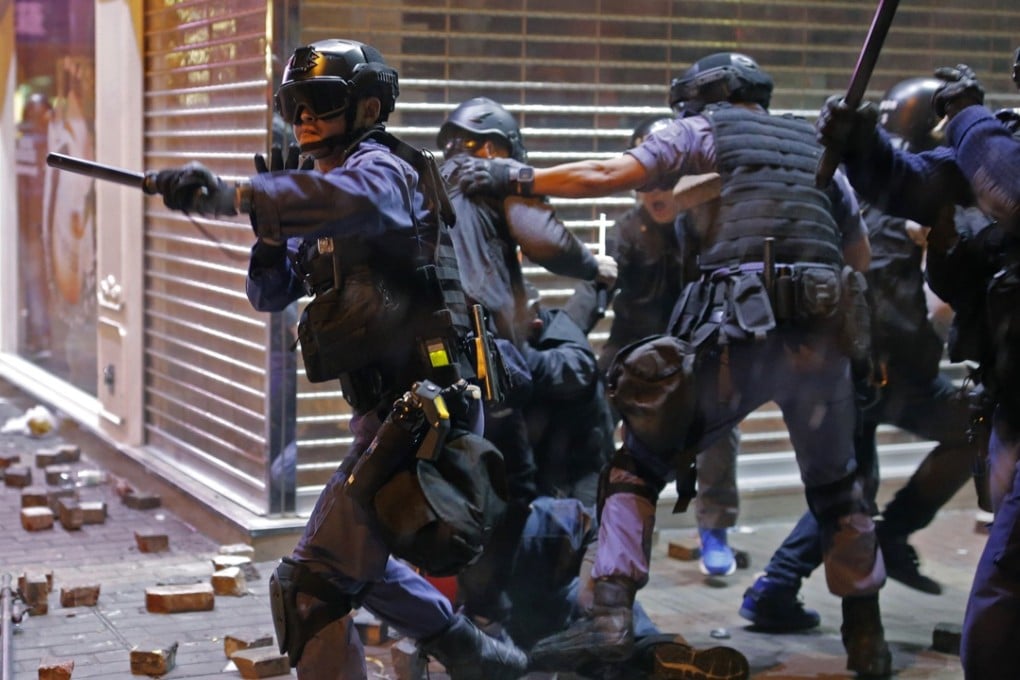 Police Tactical Unit officers react as rioters throw bricks at them in Mong Kok. Photo: AP
