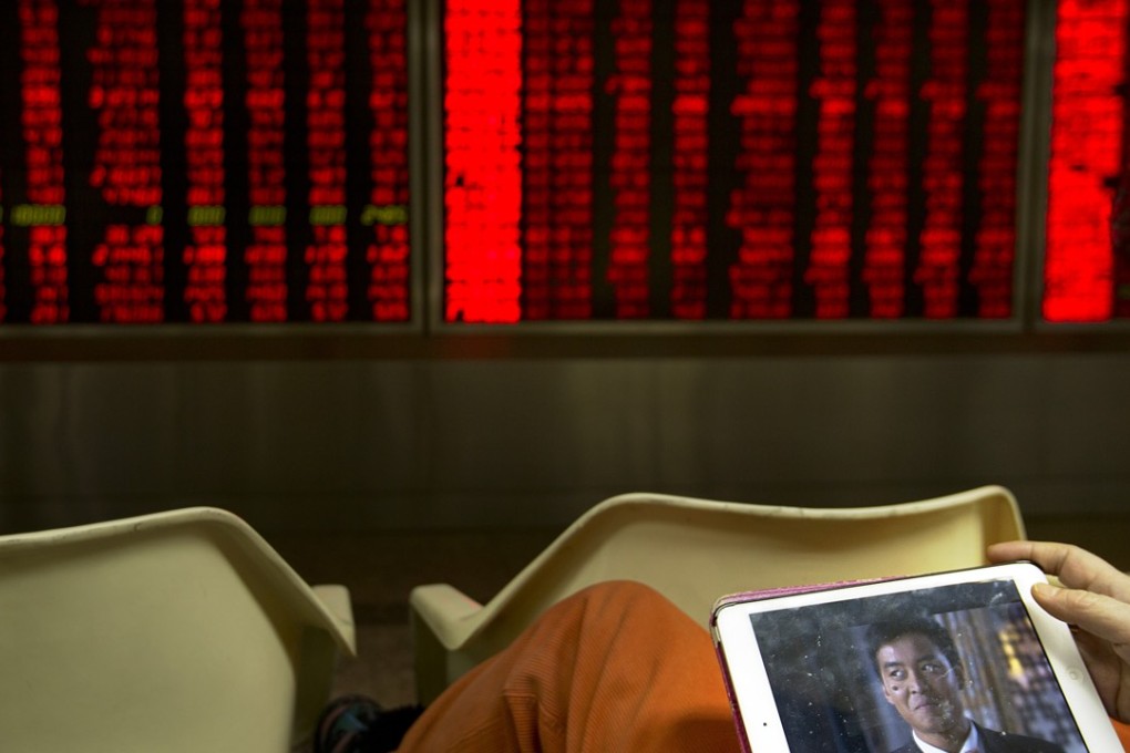 A Chinese investor watches a video on a tablet computer while monitoring stock prices in a brokerage house in Beijing, last month as a black funk seems to have settled over the global economy. Photo: AP