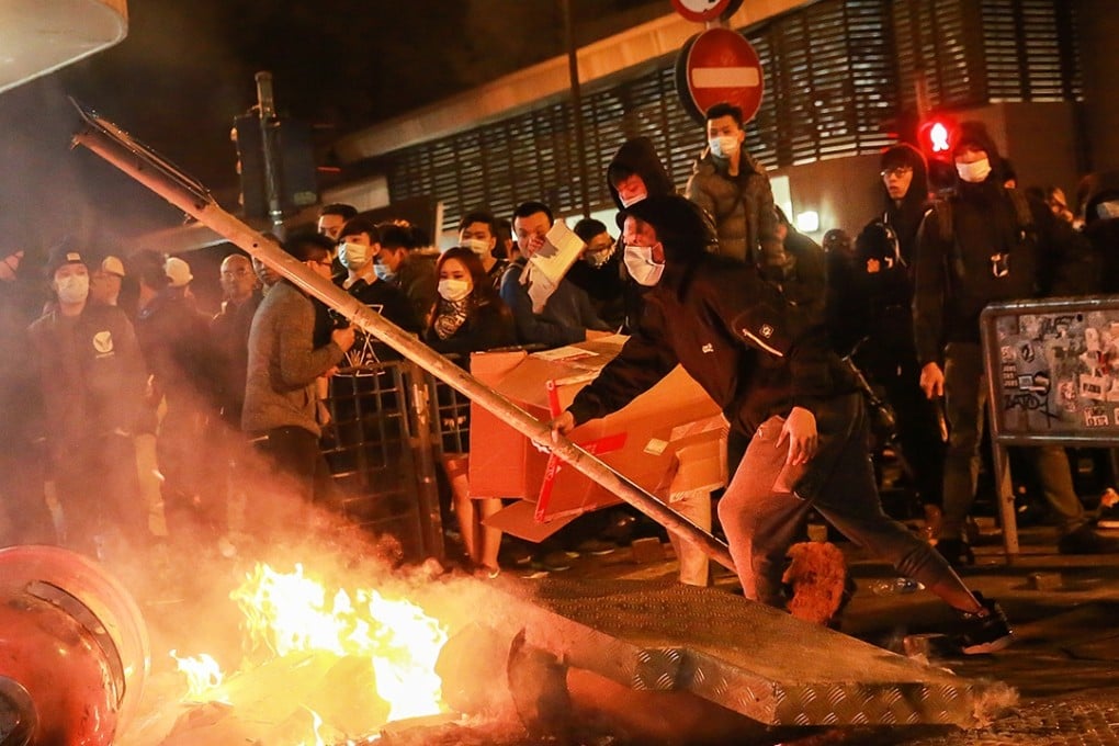 A rioter holds a lamp post as a fire burns in Mong Kok. Photo: Bloomberg