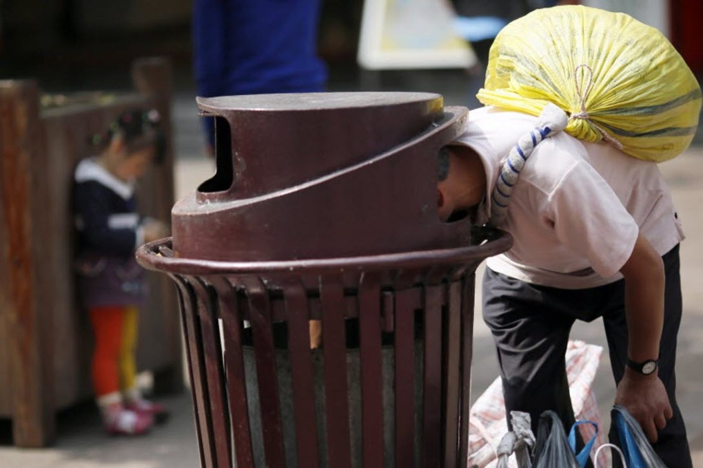 A man looks for sellable garbage from a public trash can in Shanghai. Photo: AP