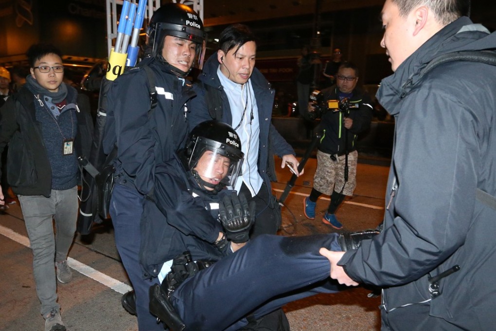 Police officers carry a colleague injured during the Mong Kok riot. Photo: SCMP Pictures