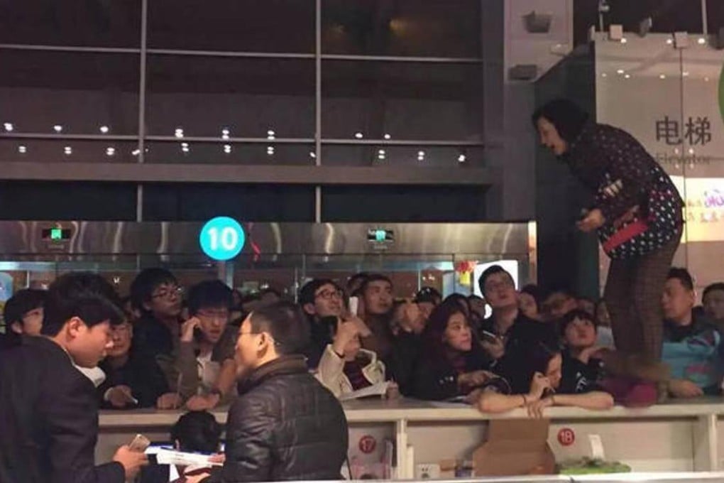 The woman leapt onto the check-in counter to complain about flight delays due to snow at Dalian airport. Photo: Sina Weibo
