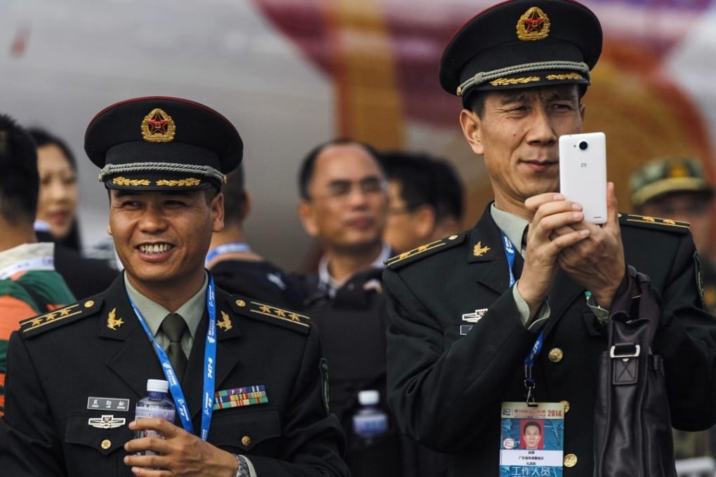 A PLA officer takes photos on his mobile phone at the Zhuhai air show in 2014. The military warned personnel this week in its daily newspaper that car hailing apps could use a phone’s GPS system to reveal sensitive information. Photo: Reuters