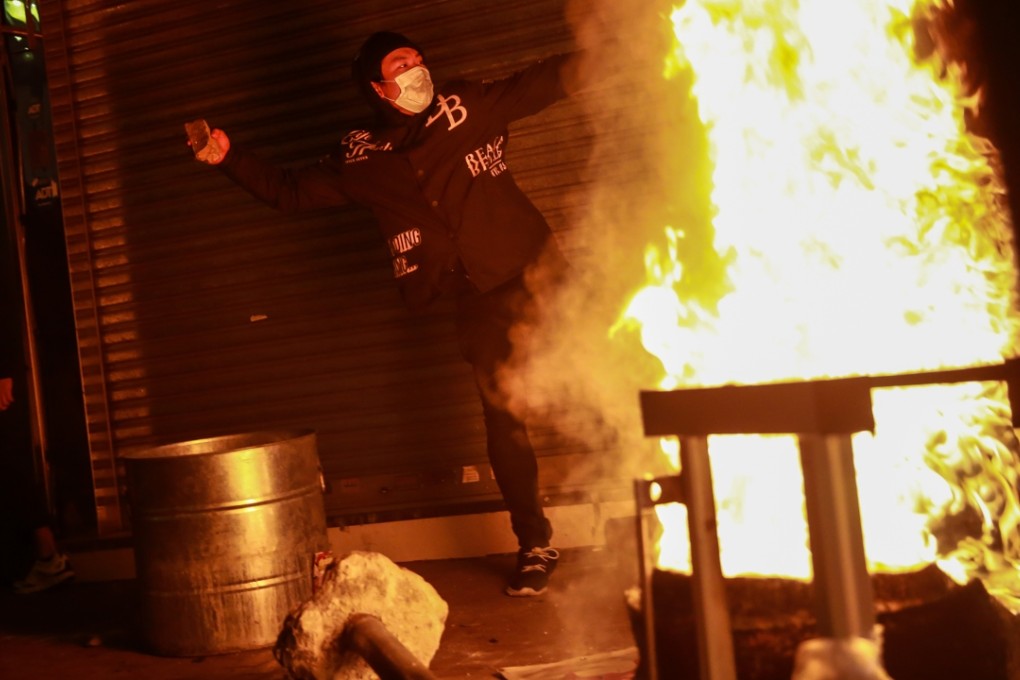 A rioter throws a brick as a fire burns in Mong Kok on February 9. Photo: Bloomberg