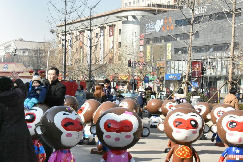 Citizens pose for photos among monkey figurines in front of a shopping mall in Jinan, capital of Shandong Province. Property consultants say neighbourhood shopping malls in the suburbs have become bright spots in the industry. Photo: Xinhua