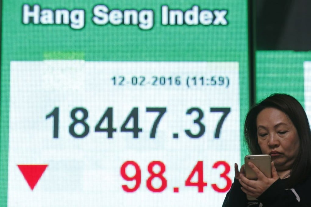 A woman uses her smartphone in front of an electronic board showing the Hong Kong index at a bank in Hong Kong last Friday as a sell-off in global markets seem to be accelerating. Photo: AP