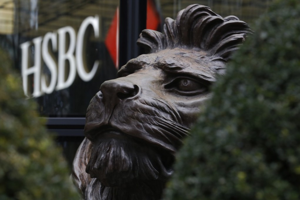 A sculpture of one of HSBC’s famous lions, seen through hedges, sits outside the main entrance to the HSBC Holdings headquarters in the Canary Wharf business, district in London. Photo: Bloomberg