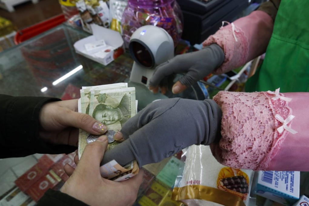 A convenience store employee returns change to a customer buying groceries in Beijing. Photo: EPA