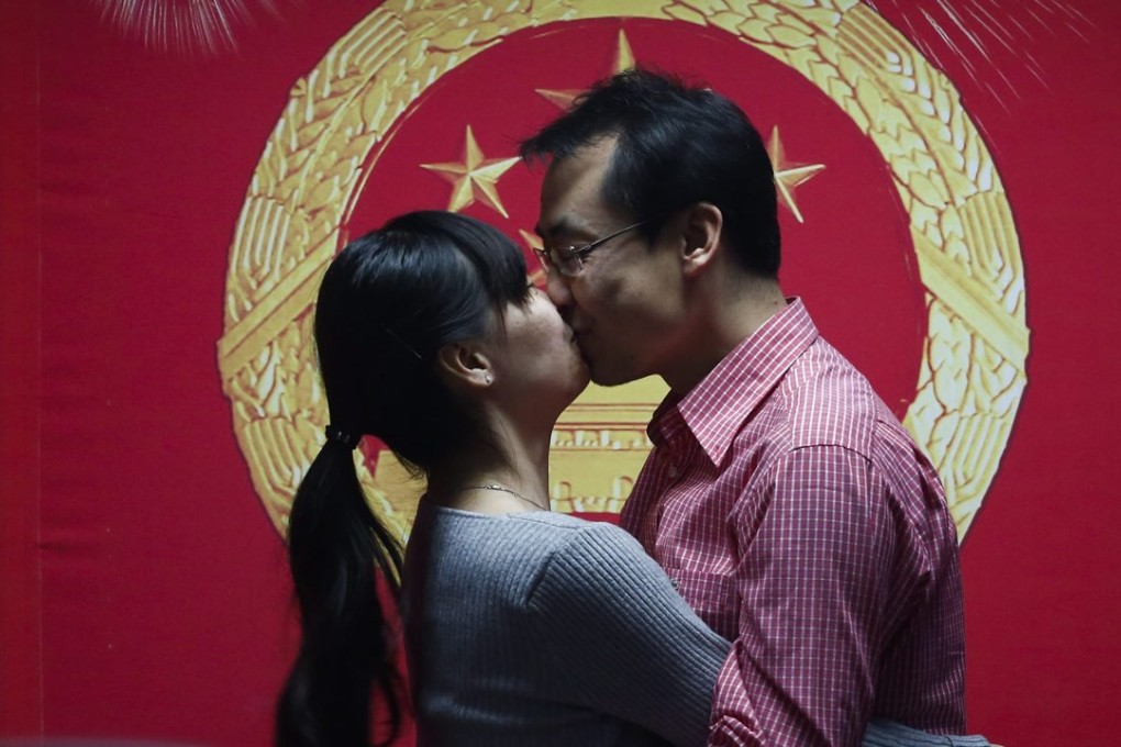 A Chinese couple kiss while being recorded on video during a ceremony to celebrate receiving their marriage licence on Valentine's Day at a marriage registry office in Beijing, Photo: EPA