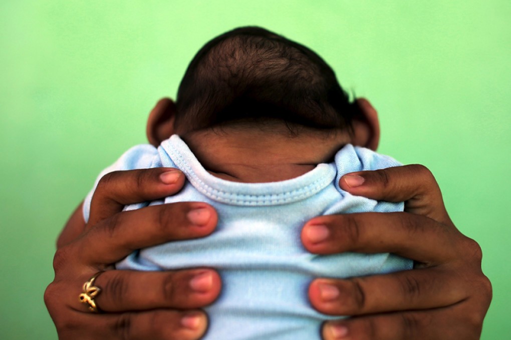 Jackeline, 26, holds her son who is 4-months old and born with microcephaly, in front of their house in Olinda, near Recife, Brazil, February 11, 2016. Recent laboratory analyses identified Zika virus infections in three people who died in Brazil last year, the health ministry said on Thursday, although authorities could not confirm that Zika alone was responsible for their deaths. REUTERS/Nacho Doce TPX IMAGES OF THE DAY