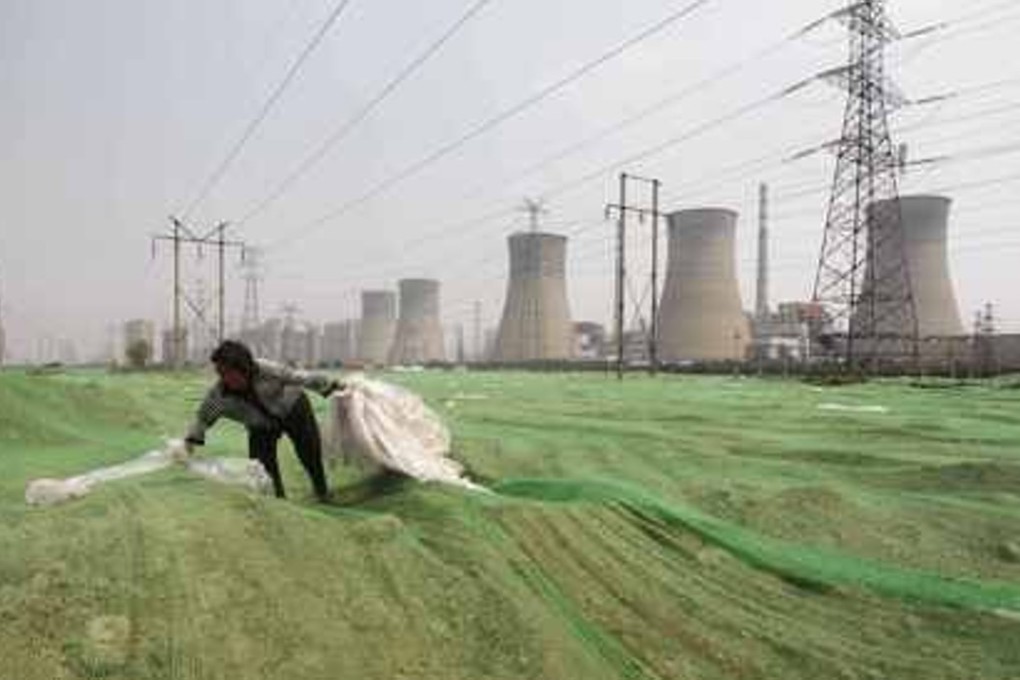 Waste not, want not: a labourer collects plastic bags on a dust screen covering construction waste near a power plant in Zhengzhou, Henan province in this file photo. China is now building a nuclear facility in Guangdong province that will produce less harmful waste. Photo: SCMP Pictures
