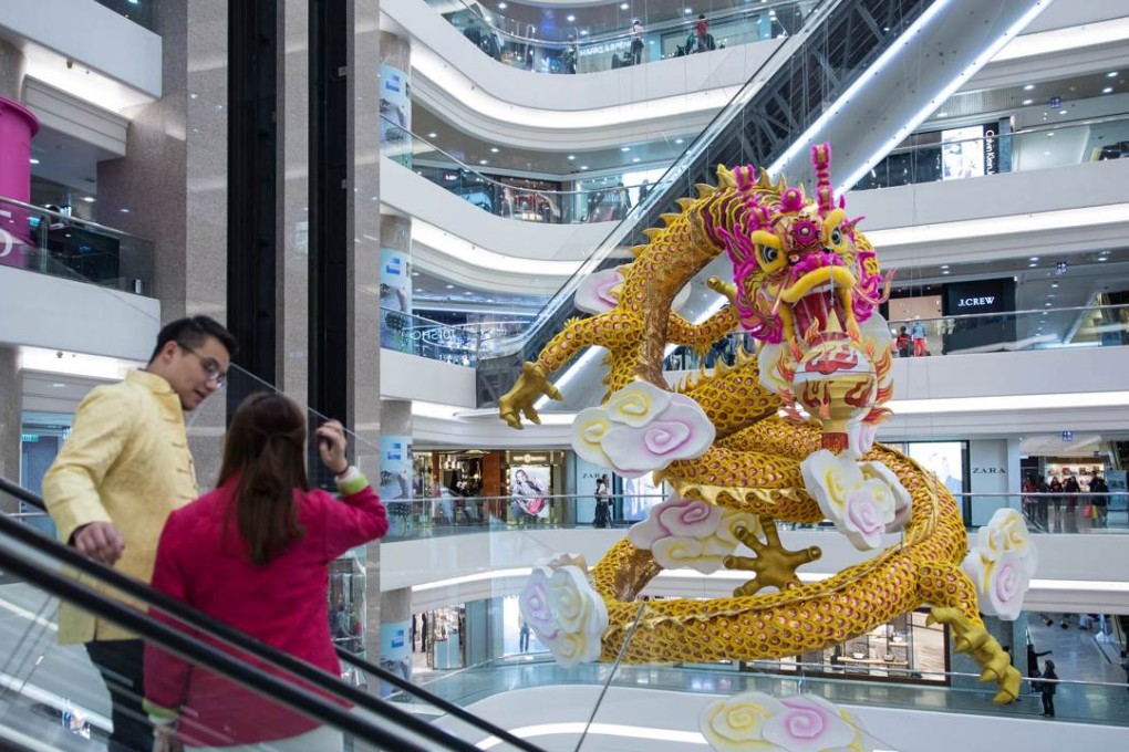 A couple ride on an escalator in front of a Chinese dragon decoration hanging in a Hong Kong shopping mall during the Lunar New Year. Photo: AFP