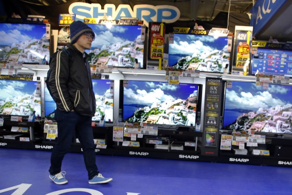 A shopper walks past Sharp Aquos flat-panel televisions at an electronics store in Tokyo. Photo: AP