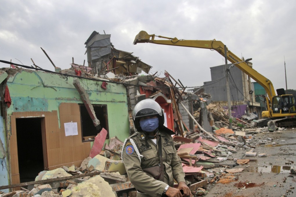 A city security officer stands guard as buildings are demolished in Kalijodo shantytown which is also a red light district. Photo: AP