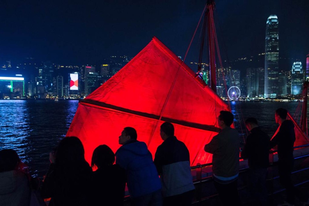 People stand on a viewing deck next to a traditional "junk" tourist boat in Hong Kong’s Victoria Harbour. The city is known for its spectacular skyline. Photo: AFP