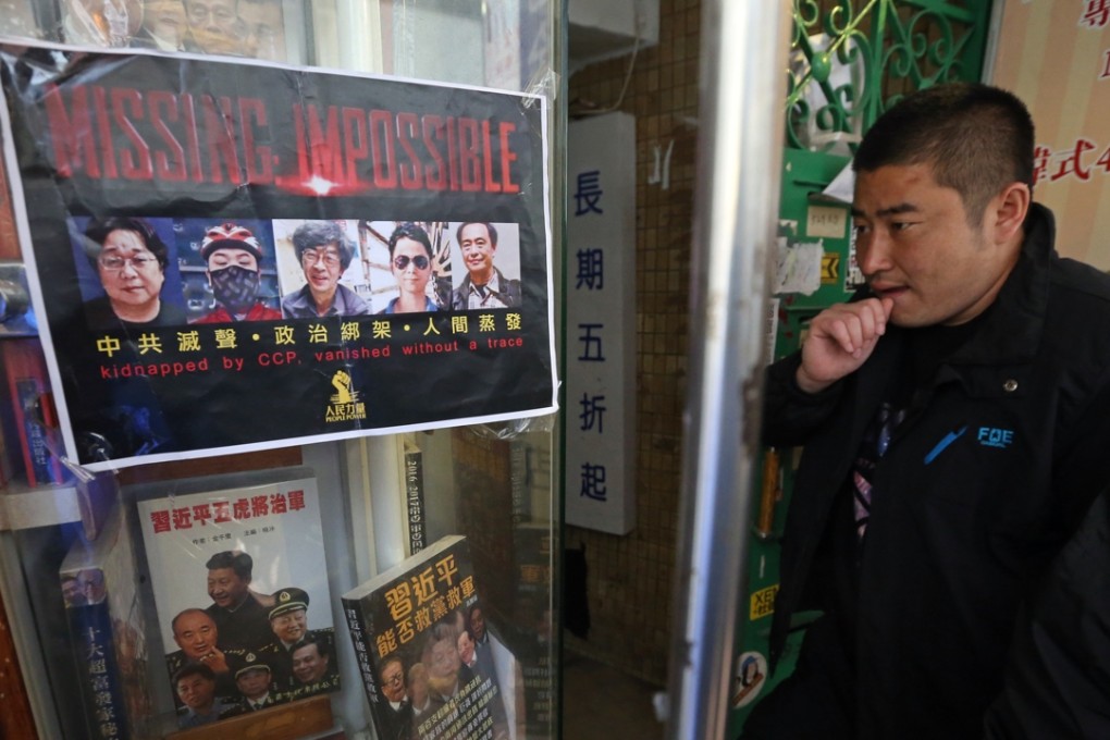 A visitor outside Causeway Bay Books looks at a poster showing the missing booksellers. Photo: K. Y. Cheng
