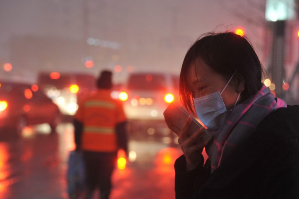 A woman wearing a mask checks her mobile phone in heavy smog in Shenyang, Liaoning province. Photo: EPA