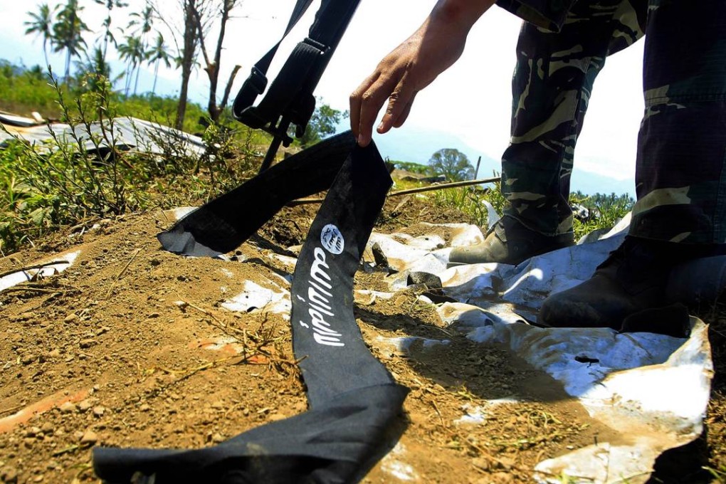 A Philippine soldier picks up the headband adorned with the logo used by Islamic State in Butig Town. Photo: AFP