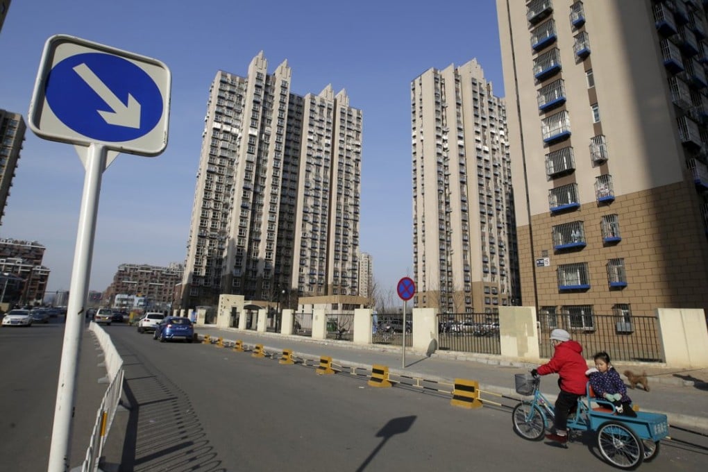 A woman rides a tricycle carrying a child near a residential compound in Beijing's Tongzhou district. Photo: Reuters