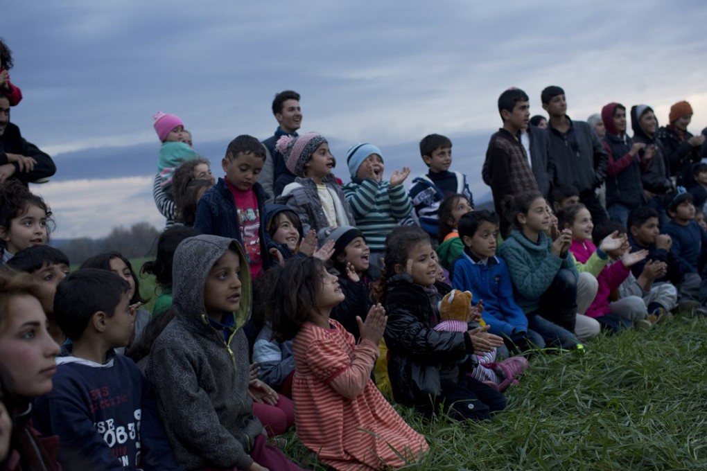 Children watch a performer on a refugee camp where thousands of refugees are waiting to be allowed to cross the border into Macedonia in the northern Greek border station of Idomeni on Thursday. Photo: AP