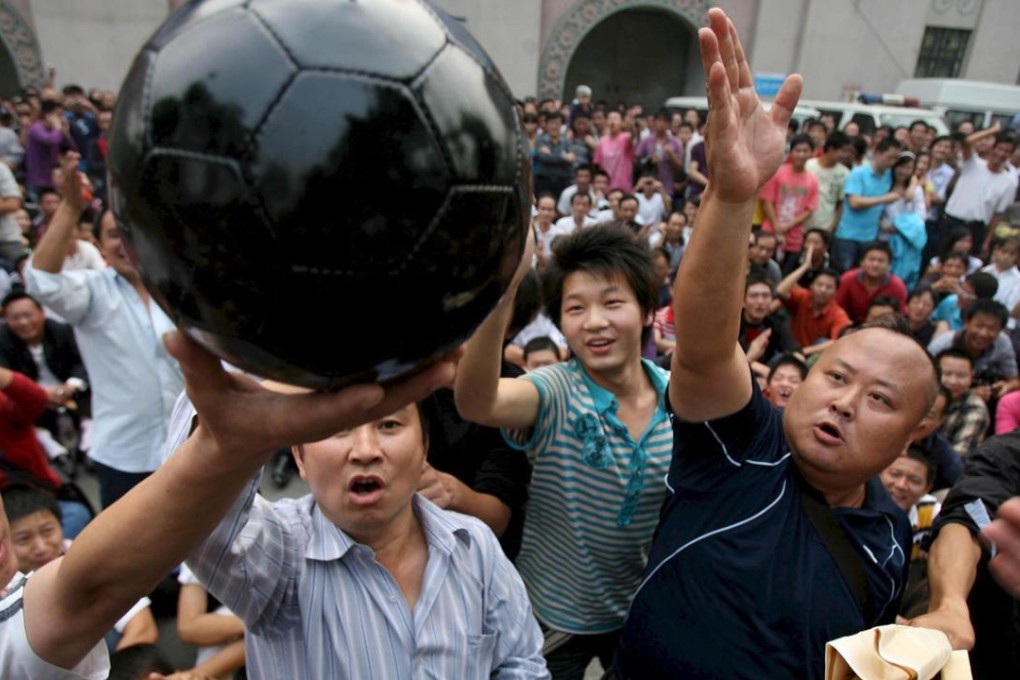 Soccer fans beat a black football which symbolises dark Chinese football industry as they protest outside a stadium in downtown Wuhan city in 2008. Despite a clampdown on corruption since then, problems still remain. Photo: EPA