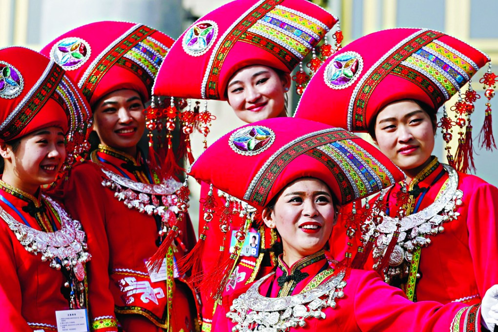 Women wearing ethnic minority costumes take selfies outside the Great Hall of the People during the opening session of the National People's Congress (NPC) in Beijing, China. Photo: Reuters